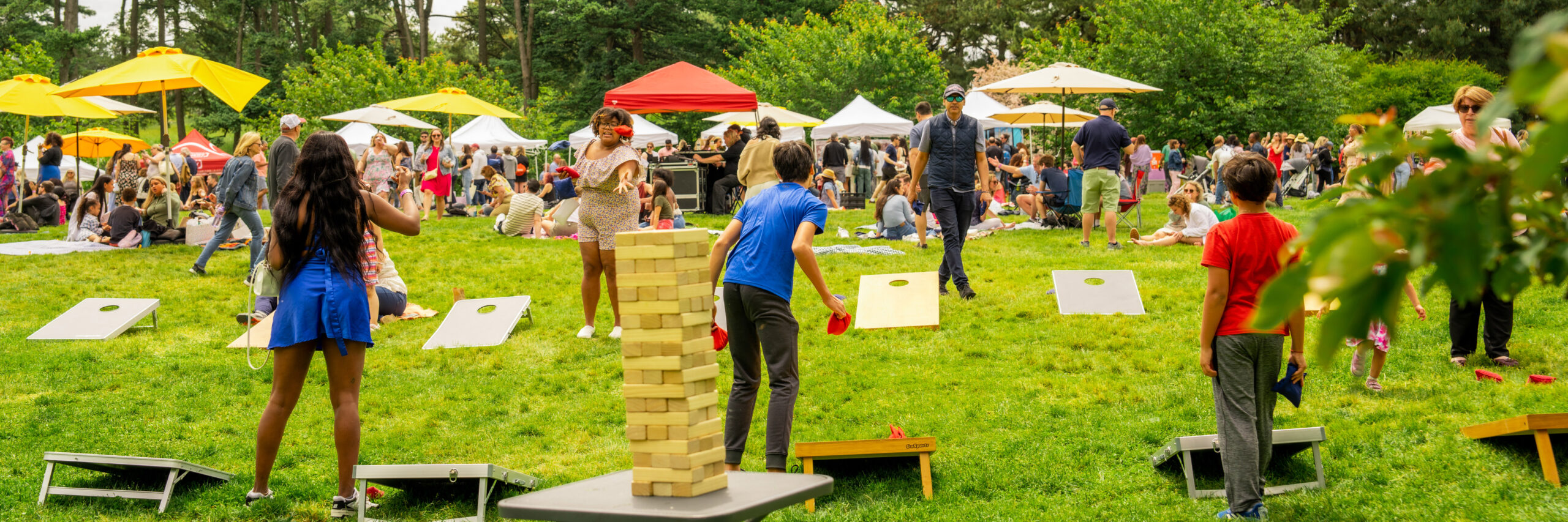 Group of people playing corn hole on a field