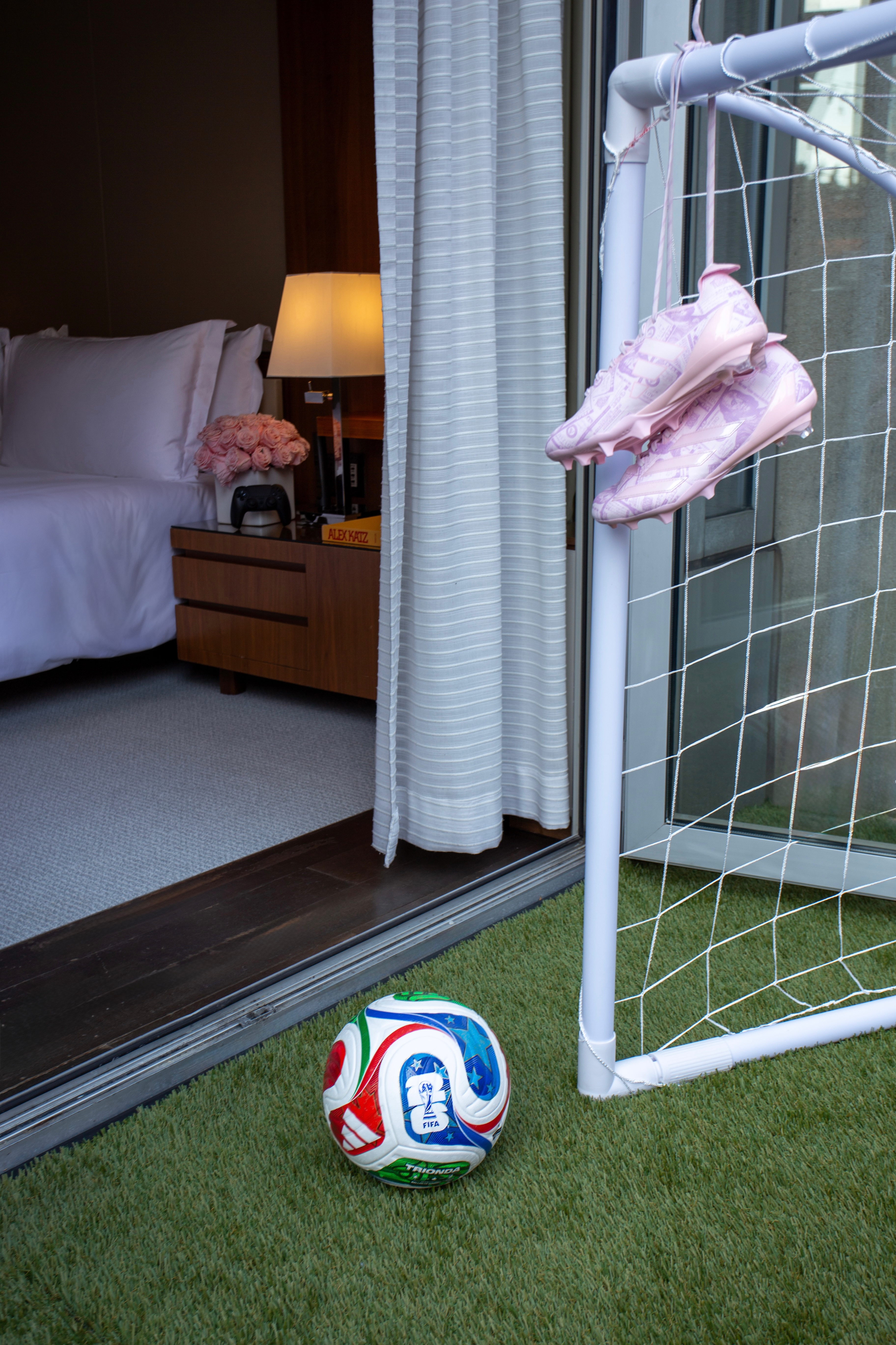 Hotel room with soccer ball and turf on terrace and pink roses