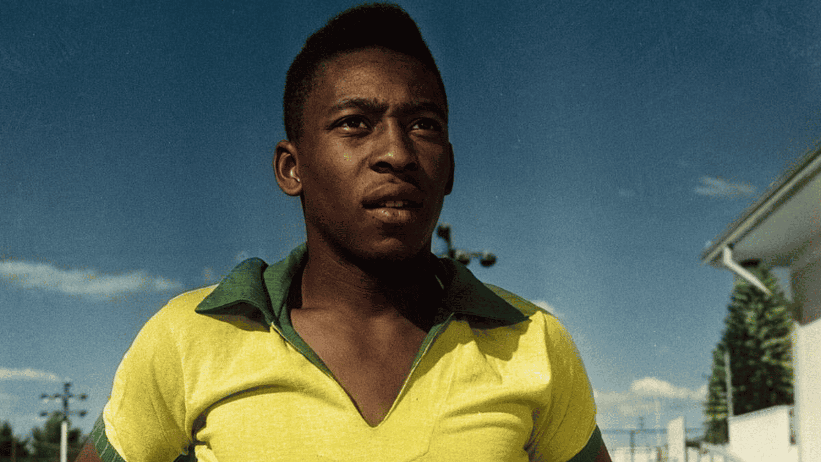 A movie still of a young Pele wearing a yellow and green Brazilian soccer jersey.